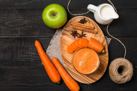 Glass of carrot juice and carrots on black wooden background, top viewの写真素材
