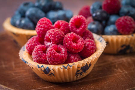 Blueberries and raspberries in a tartlets on wooden tableの写真素材