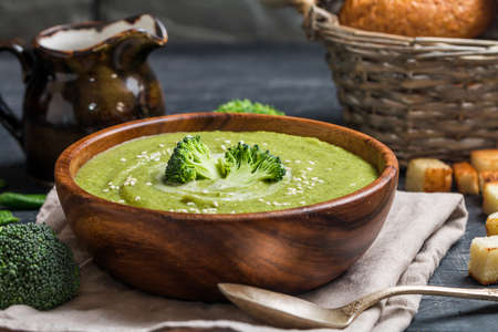 Wooden bowl of broccoli cream soup on black tableの写真素材