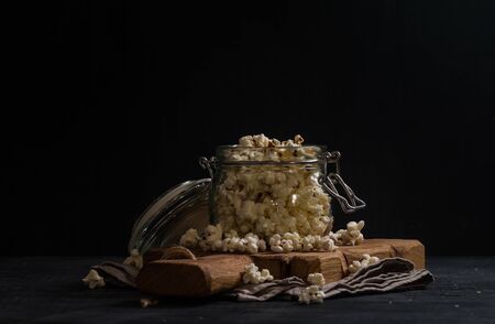 Salt popcorn in a glass jar on black backgoundの写真素材