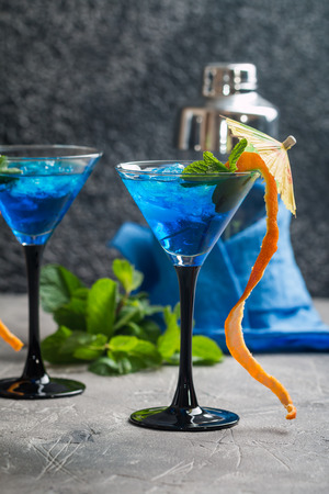 Blue cocktail with ice and mint in martini glasses on gray backgroundの写真素材