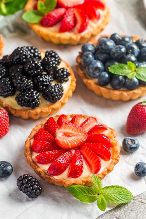 Fresh homemade berrie tarts with blueberries, blueberry and strawberries on gray backgroundの写真素材