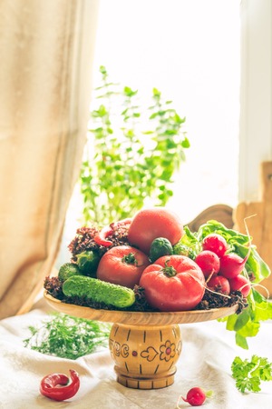 Still life of fresh vegatables in a wooden plate on lite backgroundの写真素材