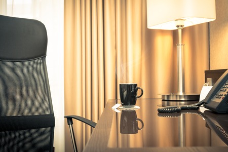 Black cup of hot tea on a glass table in a hotel roomの写真素材