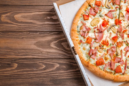 Delicious pizza with mushrooms and ham served on wooden table, top viewの写真素材