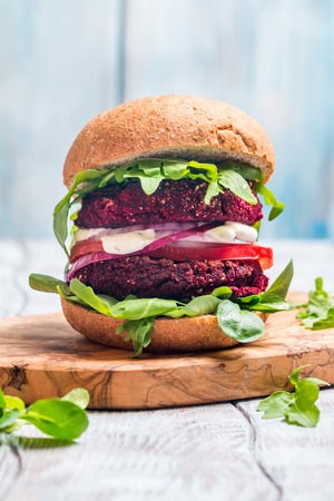 Vegetarian burger made of beetroot, tomato, corn salad and arugula on wooden backgroundの写真素材