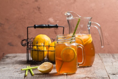 jar of lemon ice tea with straw on wooden backgroundの写真素材