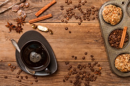 Espresso with coffee beans and cookies in muffin tin pan on wooden background, top view