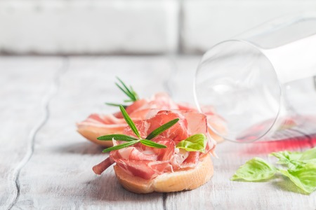 Concept of italian food with red wine and bruschetta with prosciutto on white backgroundの写真素材