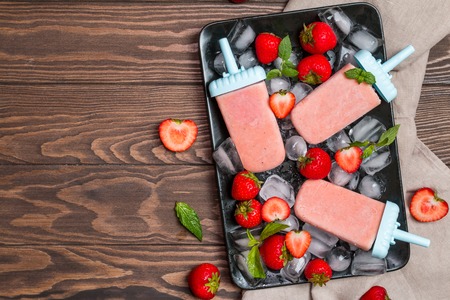 Homemade strawberry ice cream or ice on dark wooden table, frozen fruit juice, vegetarian food, top viewの写真素材