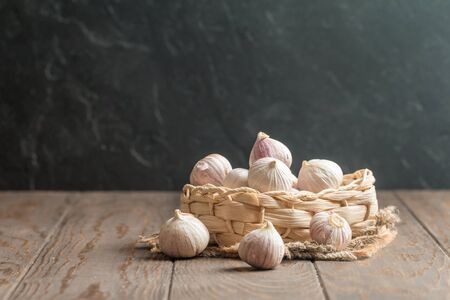 Small Garlic in a basket on wooden backgroundの写真素材