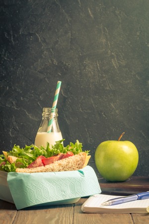 School lunch with sandwich, milk and apple on dark backgroundの写真素材