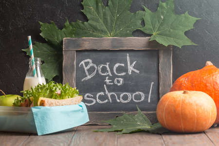 autumn still life with chalkboard, lunchbox and pumpkins on dark backgroundの写真素材