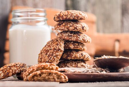 Oatmeal cookies with milk on cutting board on rustic wooden tableの写真素材