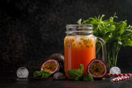 Homemade lemonade with passion fruit, mint leaves and ice cubes on black background.の写真素材