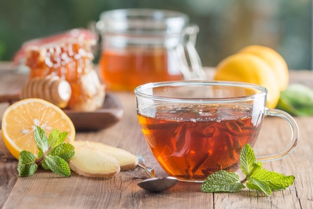 Cup of ginger tea with honey and lemon on wooden tableの写真素材