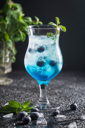 Blueberry cocktail with ice and mint in a glass, over black backgroundの写真素材