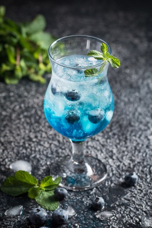 Blueberry cocktail with ice and mint in a glass, over black backgroundの写真素材