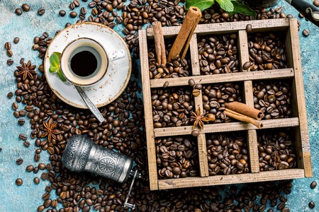 coffee beans in old wooden box, and ceramic cup of fresh making coffee over blue stone background. top viewの写真素材