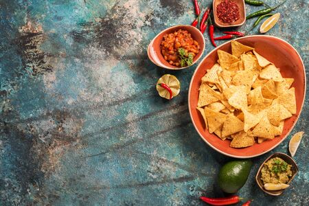 Nachos in plate with guacamole, ground beef and other sauces on blue stone background, top viewの写真素材