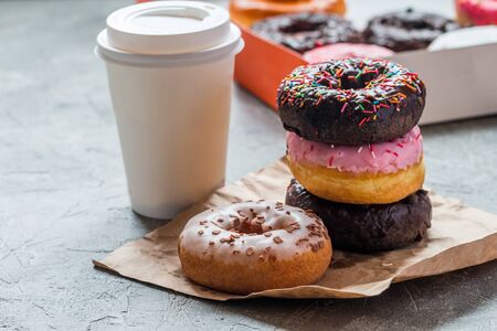 Stack of assorted donuts on a paper with coffee on gray backgroundの写真素材