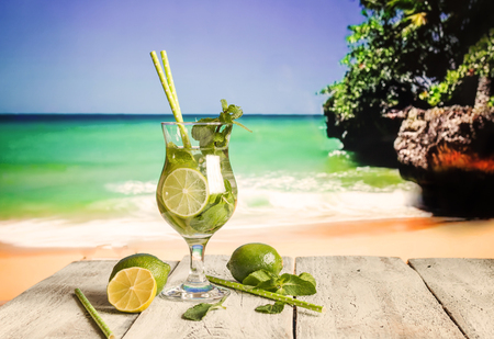 Fresh mojito cocktail on white wooden table with blue sea as a background.の写真素材