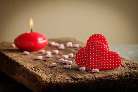 Two red hearts with heart shaped candies and candle on wooden background, valentine's day conceptの写真素材