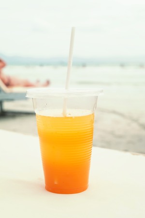 Orange juice in a glass on the beach. Summer concept.