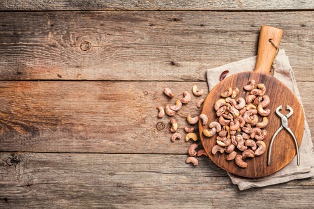 Roasted cashew nuts with salt on cutting board over textured wooden backgroundの写真素材