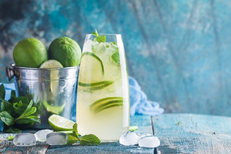 Mojito cocktail with lime and mint in highball glass on blue background