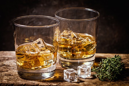 Whiskey with ice in glasses on rustic wood background, copy spaceの写真素材