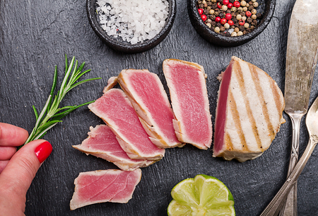 Close up of seared grilled tuna steaks on slate surface with spices and lemon, top viewの写真素材