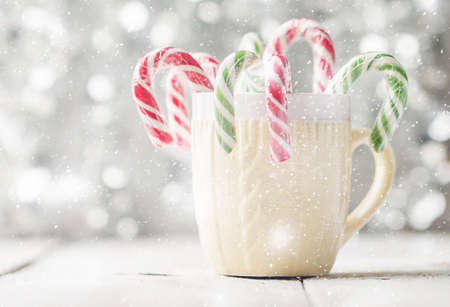 A knitted print cup with Christmas candies in front of white bokeh background