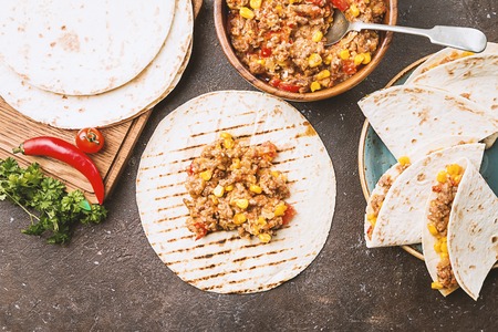 Homemade beef meat mexican fajitas with bell pepper, corn and tortilla over dark background, top...