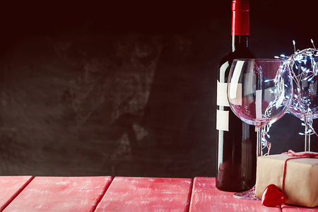 Valentines day background with red wine, wine glass and gift box over black backgroundの写真素材