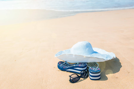 hat, sun glasses and flip flops over the sandの写真素材
