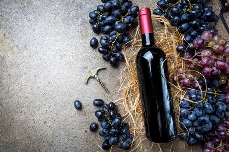 A bottle of red wine with grapesの写真素材