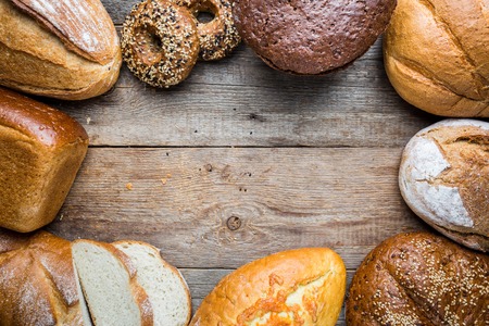 Assortment of fresh baked bread and buns on wooden table background, top viewの写真素材