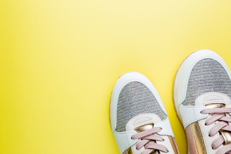 Fashion blog look. White womens sneakers with pink and gold color on yellow background. Flat lay, top view beauty female background.の写真素材