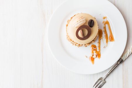 Caramel coffee cake in a glaze with nuts on plate over white background, top viewの写真素材