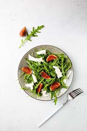 Delicious salad with figs, arugula and goat cheese on white plate, top view, copy spaceの写真素材
