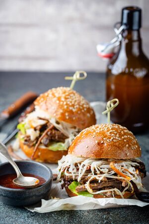 Pulled beef burger with cabbage salad and bbq sauce on paperの写真素材