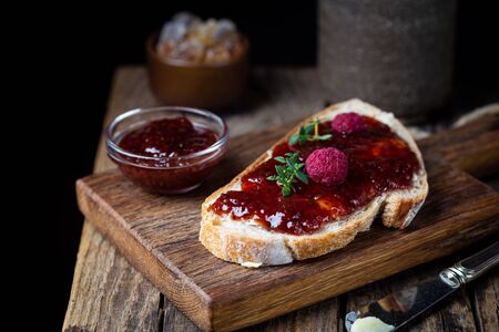 Toasted bread with sweet raspberry jam for breakfast on dark wooden backgroundの写真素材