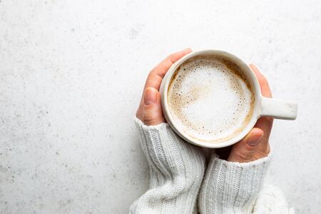 Cup of coffee in womens hand on white background, top viewの写真素材