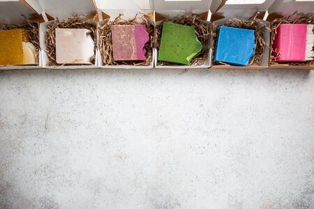 Different colorful pieces of natural homemade soap with herbs, fruits and flowers, top view