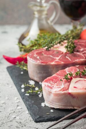 Fresh veal shank slices beef meat for Osso Buco cooking on cutting board with ingredients and seasonings thyme, pepper, salt.の写真素材