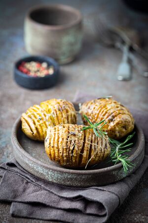 Baked hasselback potatoes with cheese, garlic and greensの写真素材