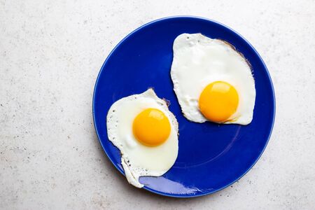 Fried eggs for breakfast on a plate, top view, copyspaceの写真素材
