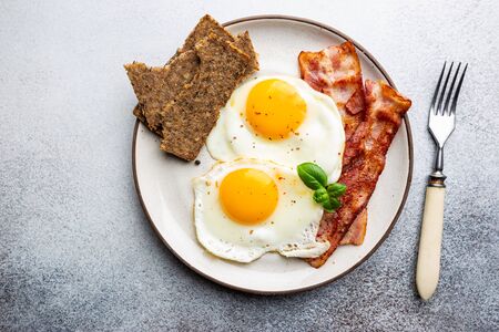 Fried eggs and bacon for breakfast on a plate, top view, copyspaceの写真素材