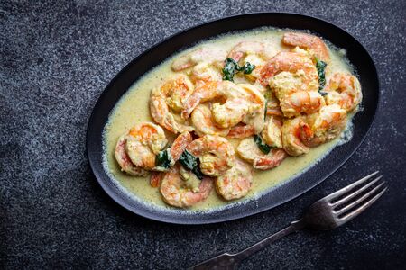 Shrimps in cream sauce with Coconut milk on a plate over black background, top view or view from above, flat layの写真素材